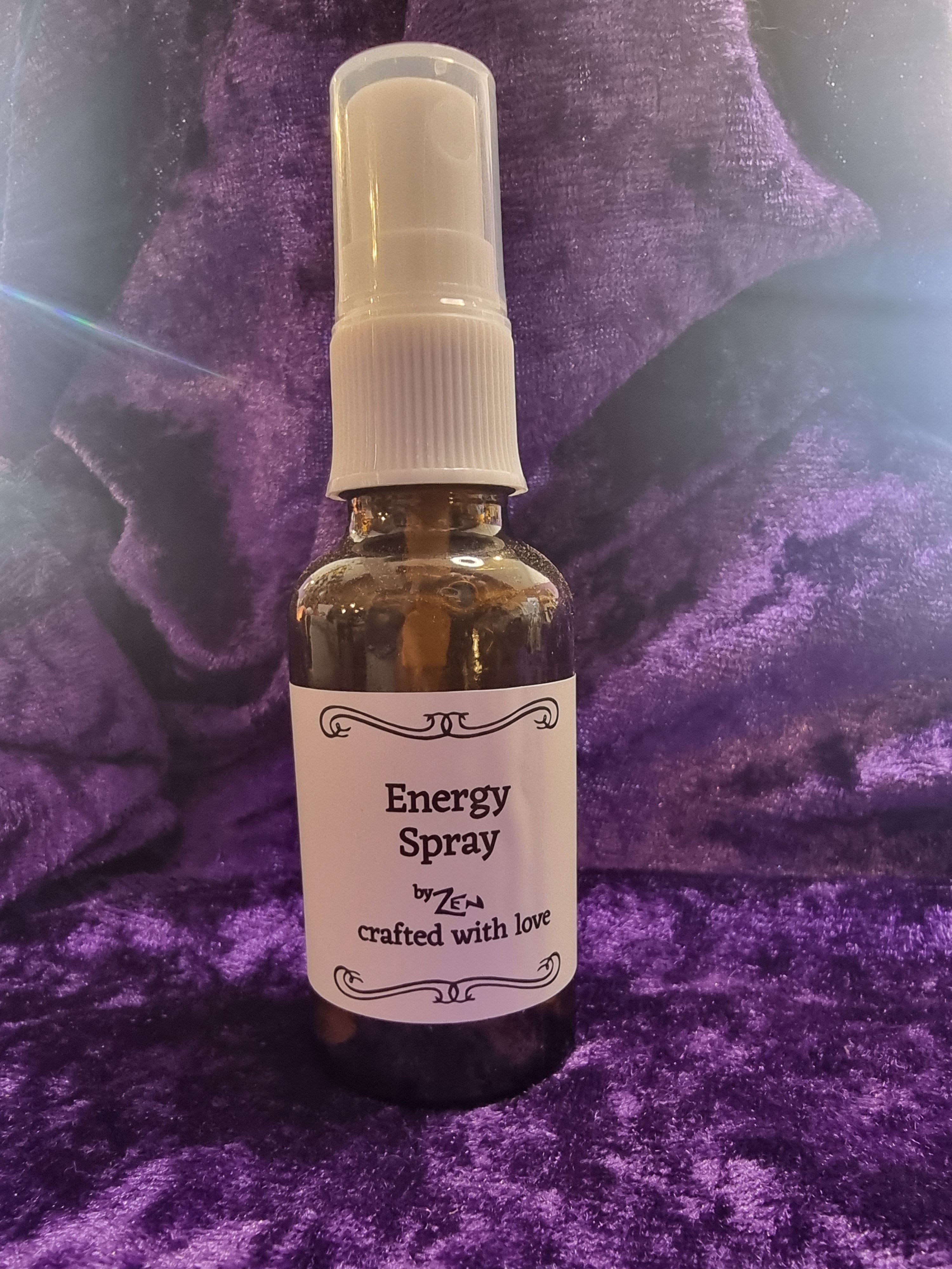 Small spray bottle labeled 'Energy Spray' on a purple textured surface