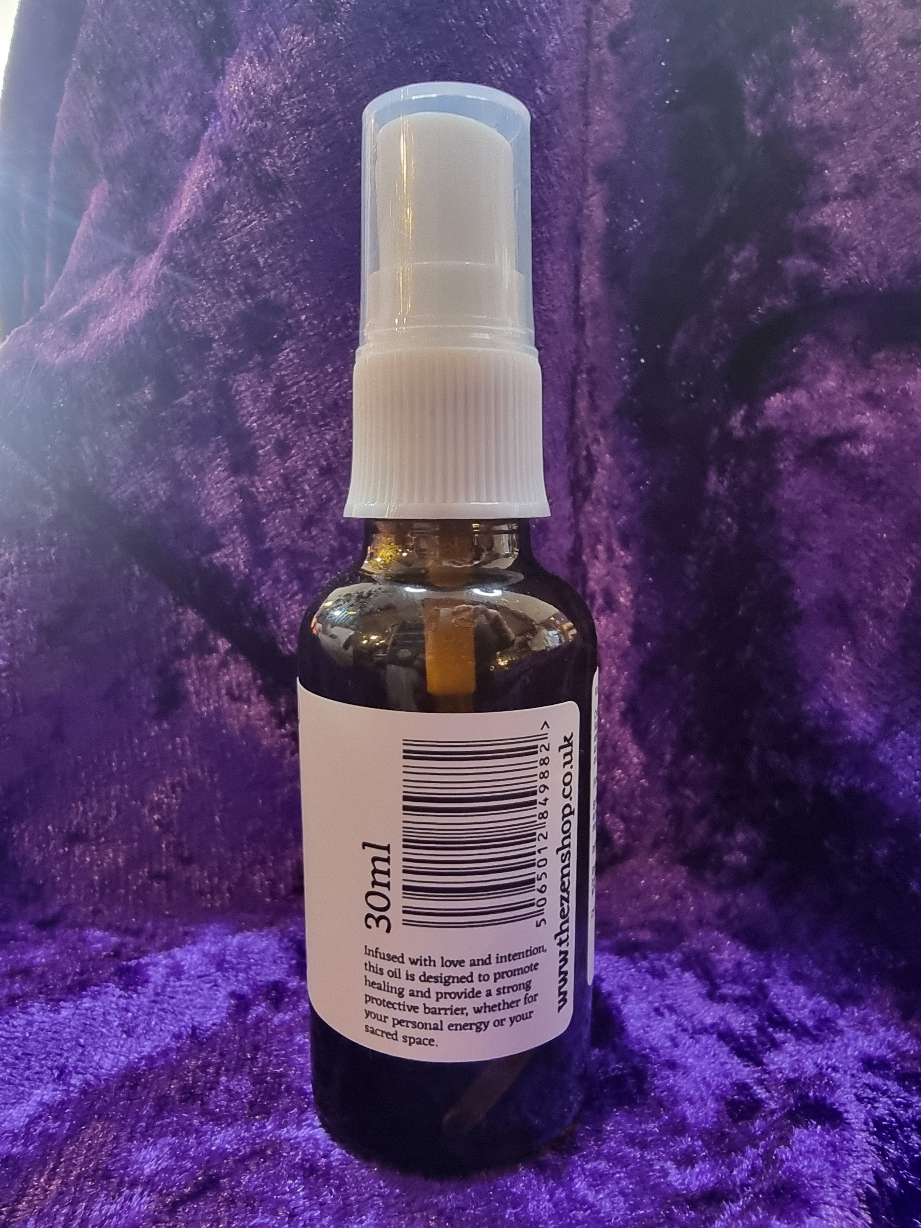 Small spray bottle with a label on a purple textured surface
