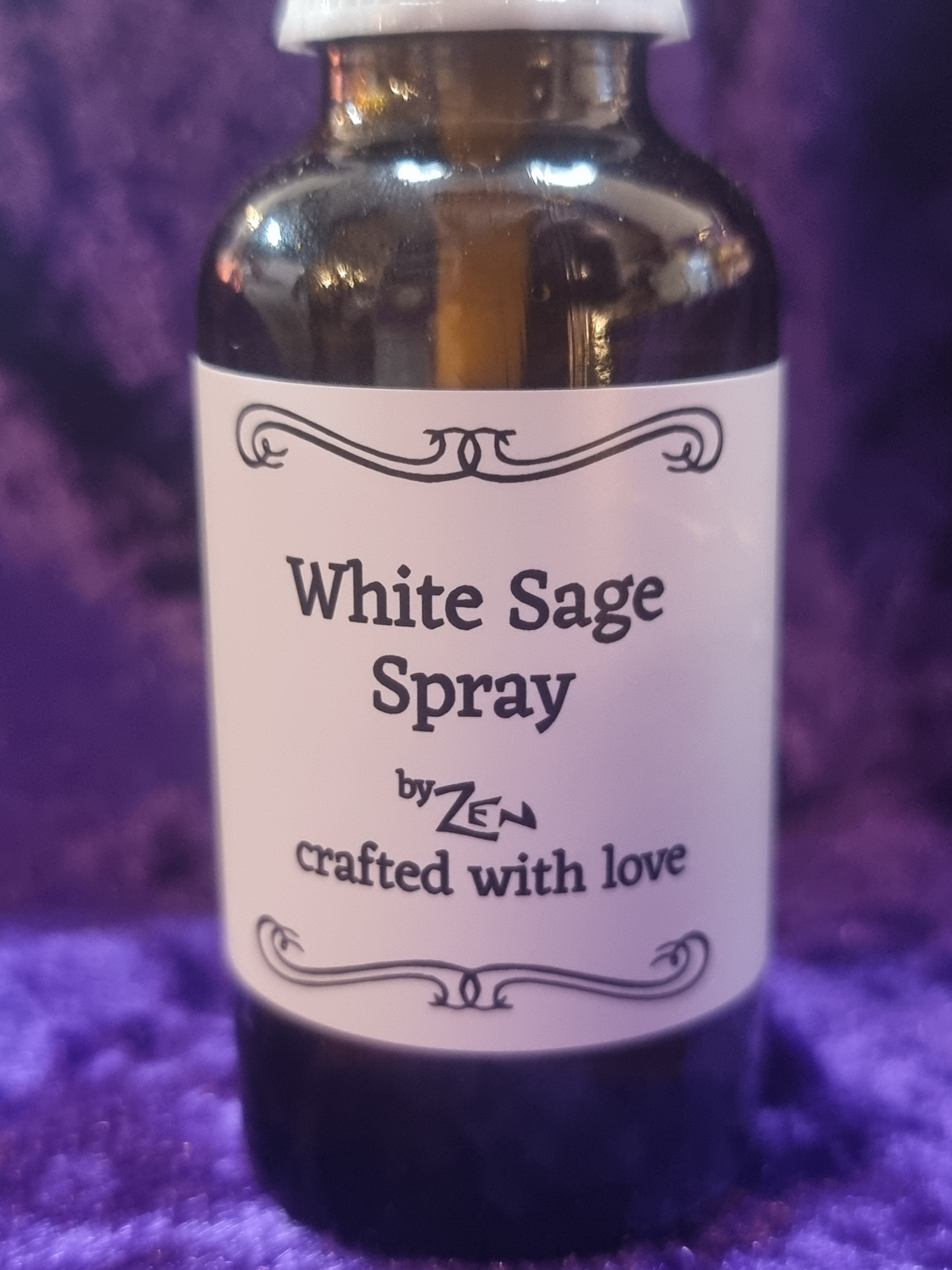 White Sage Spray bottle with a label on a purple textured background