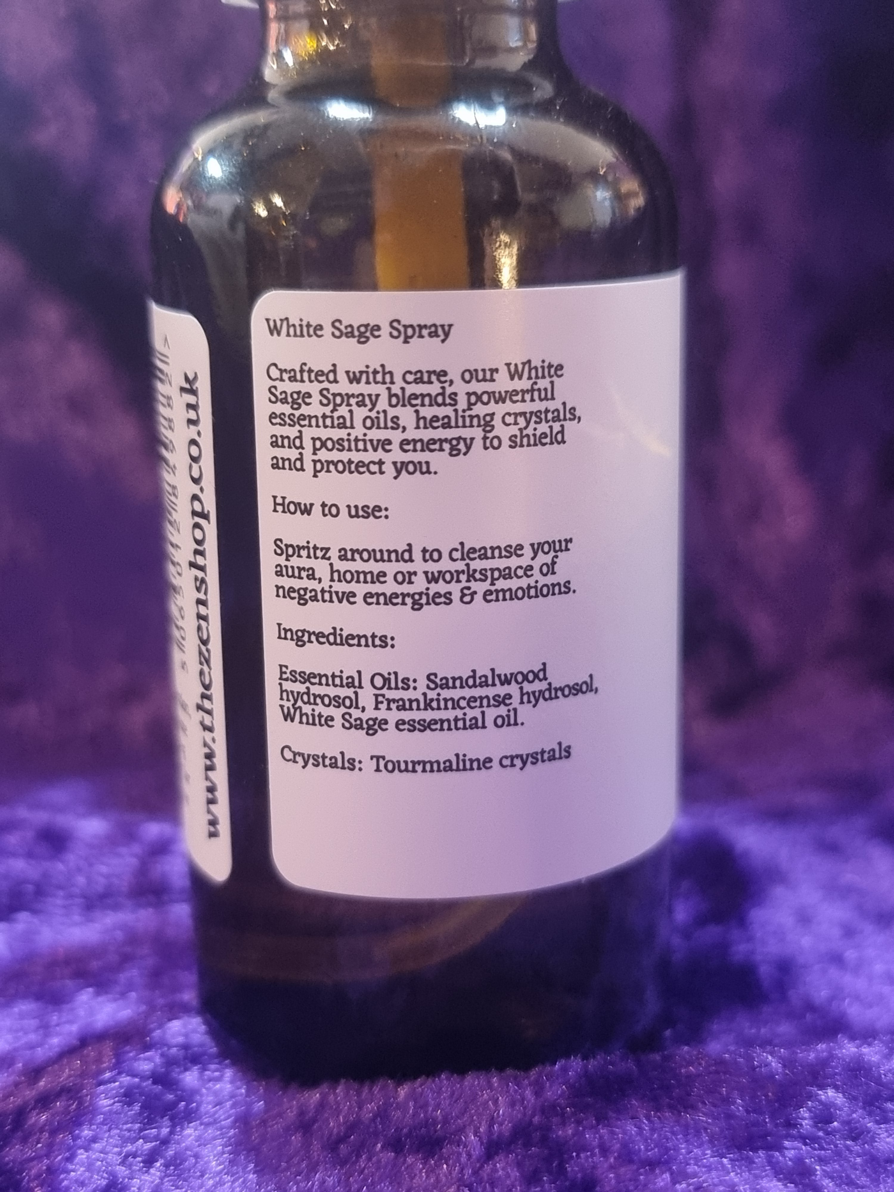 Bottle of White Sage Spray with label on a purple textured surface