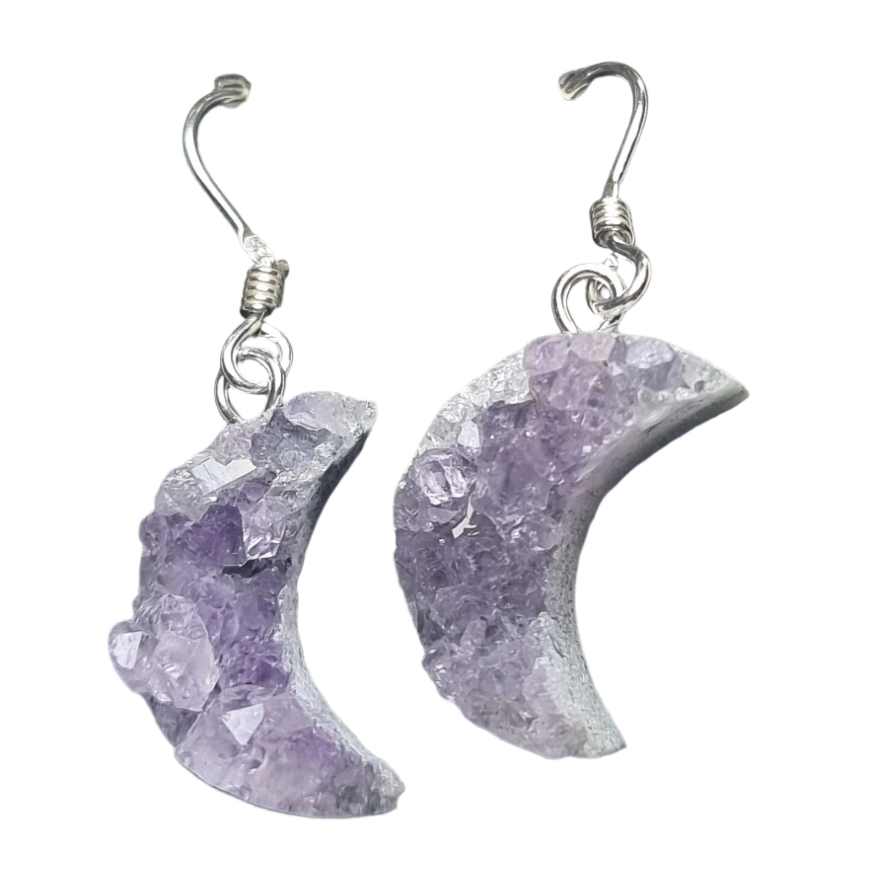 A pair of Amethyst crystal earrings, shaped in a crescent moon form, with silver hooks.