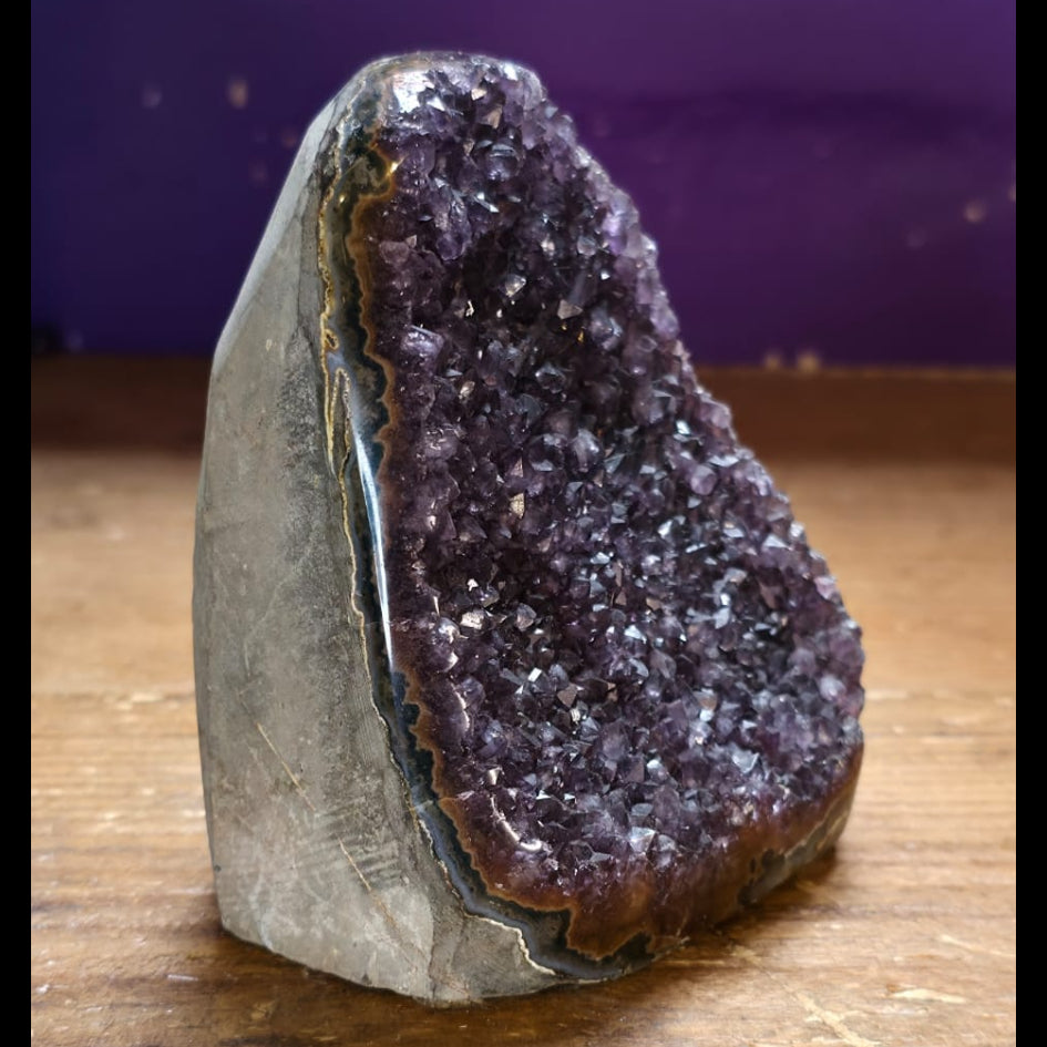 Amethyst geode on a wooden surface with a purple background