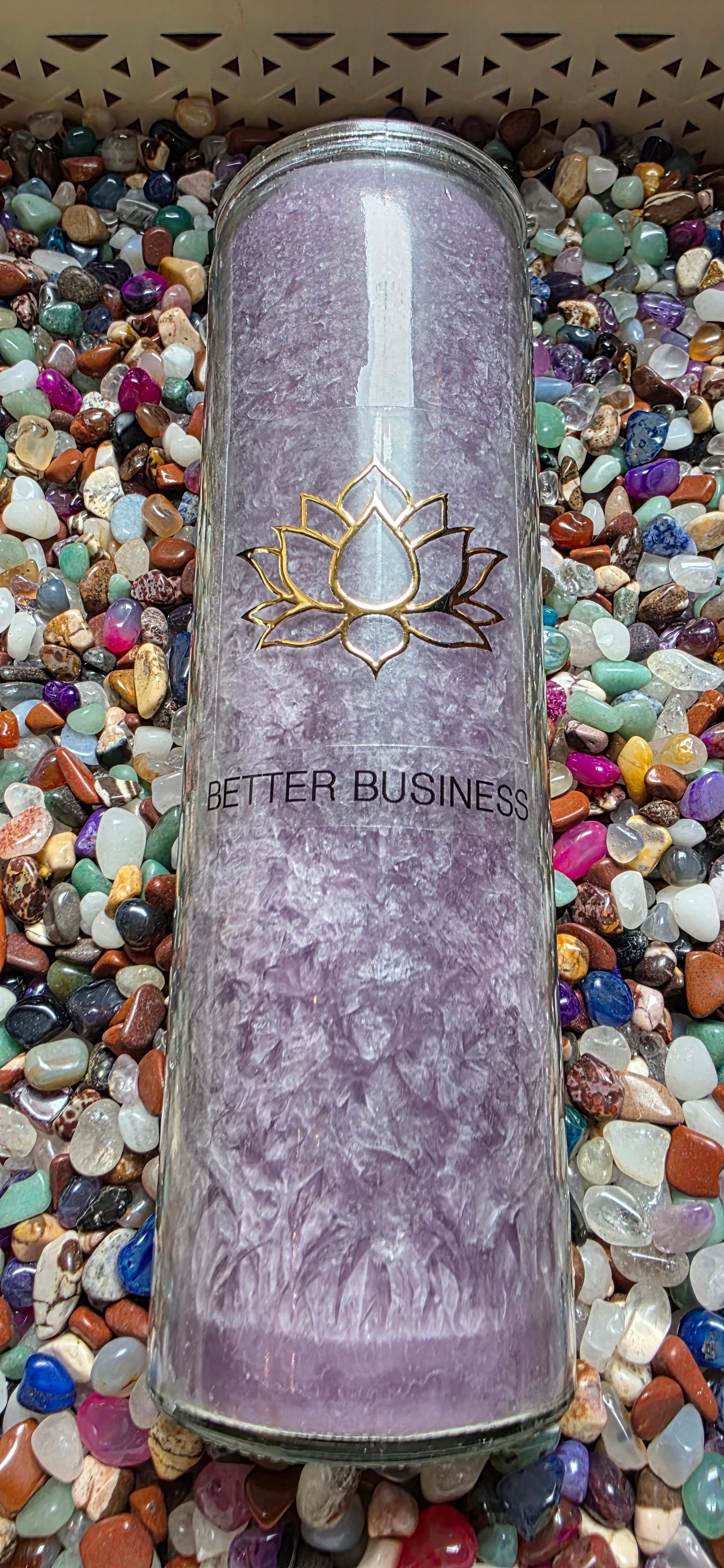 Purple cylindrical container with 'Better Business' branding on a bed of multicolored stones.