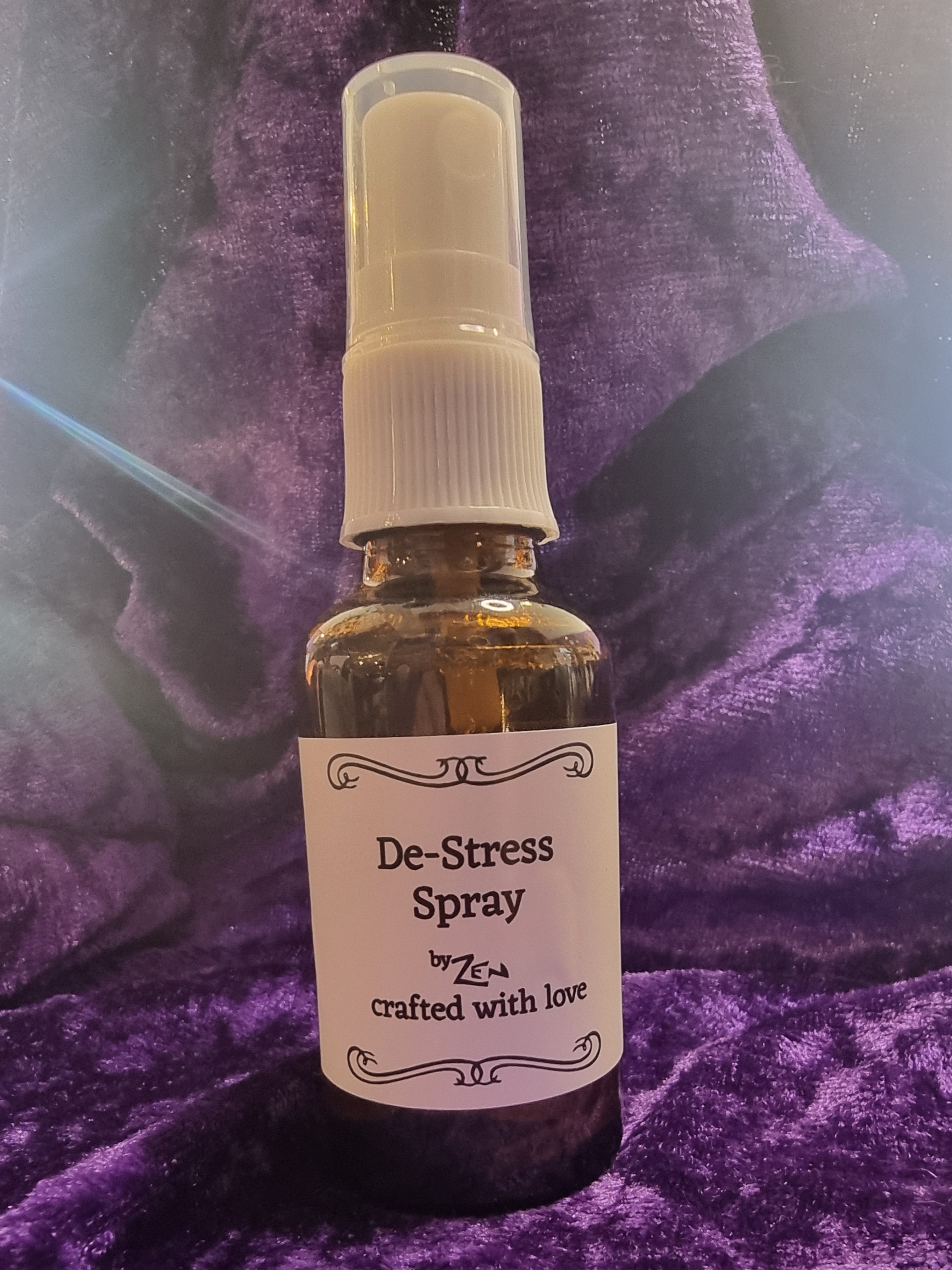Small bottle labeled 'De-Stress Spray' on a purple textured surface