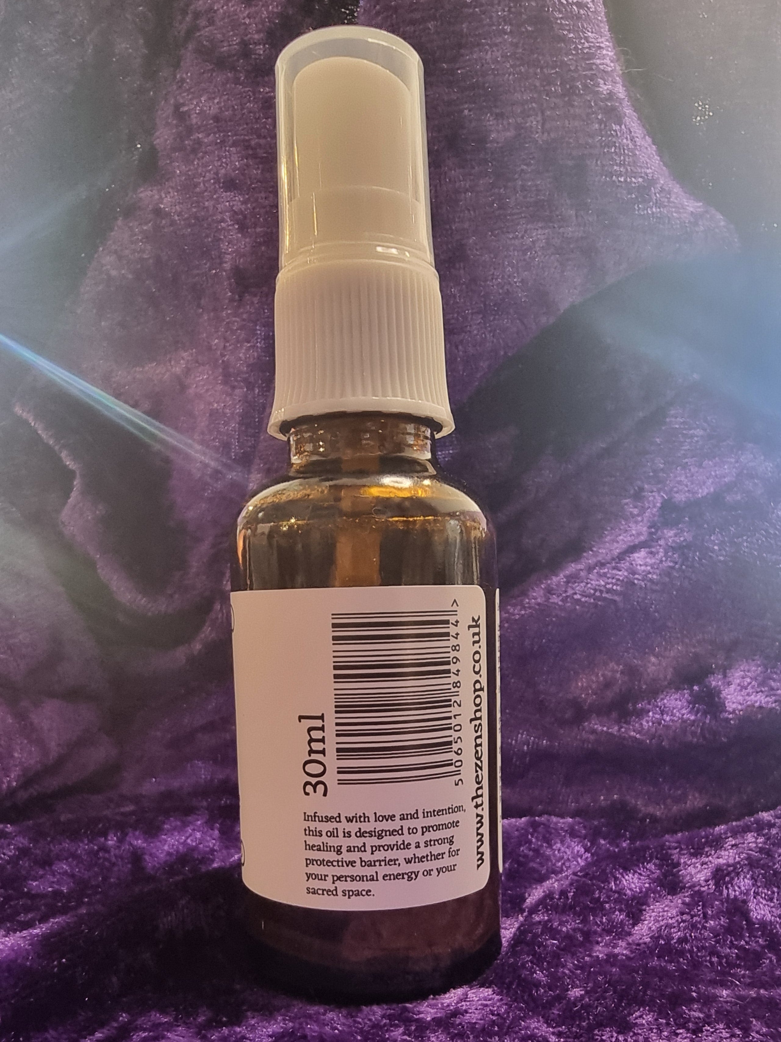Small bottle with a spray nozzle on a purple textured surface