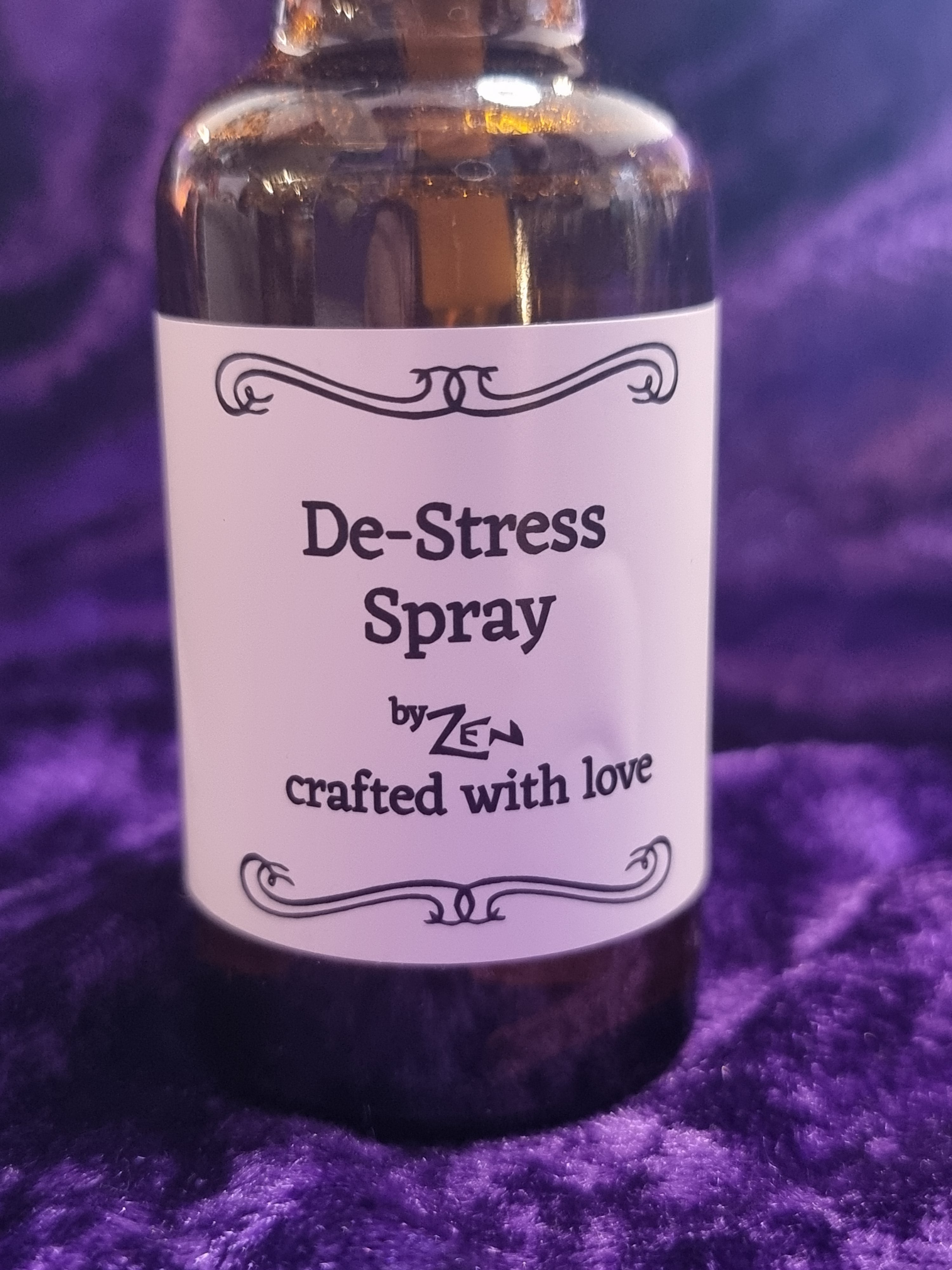 Bottle of De-Stress Spray with a label on a purple textured background