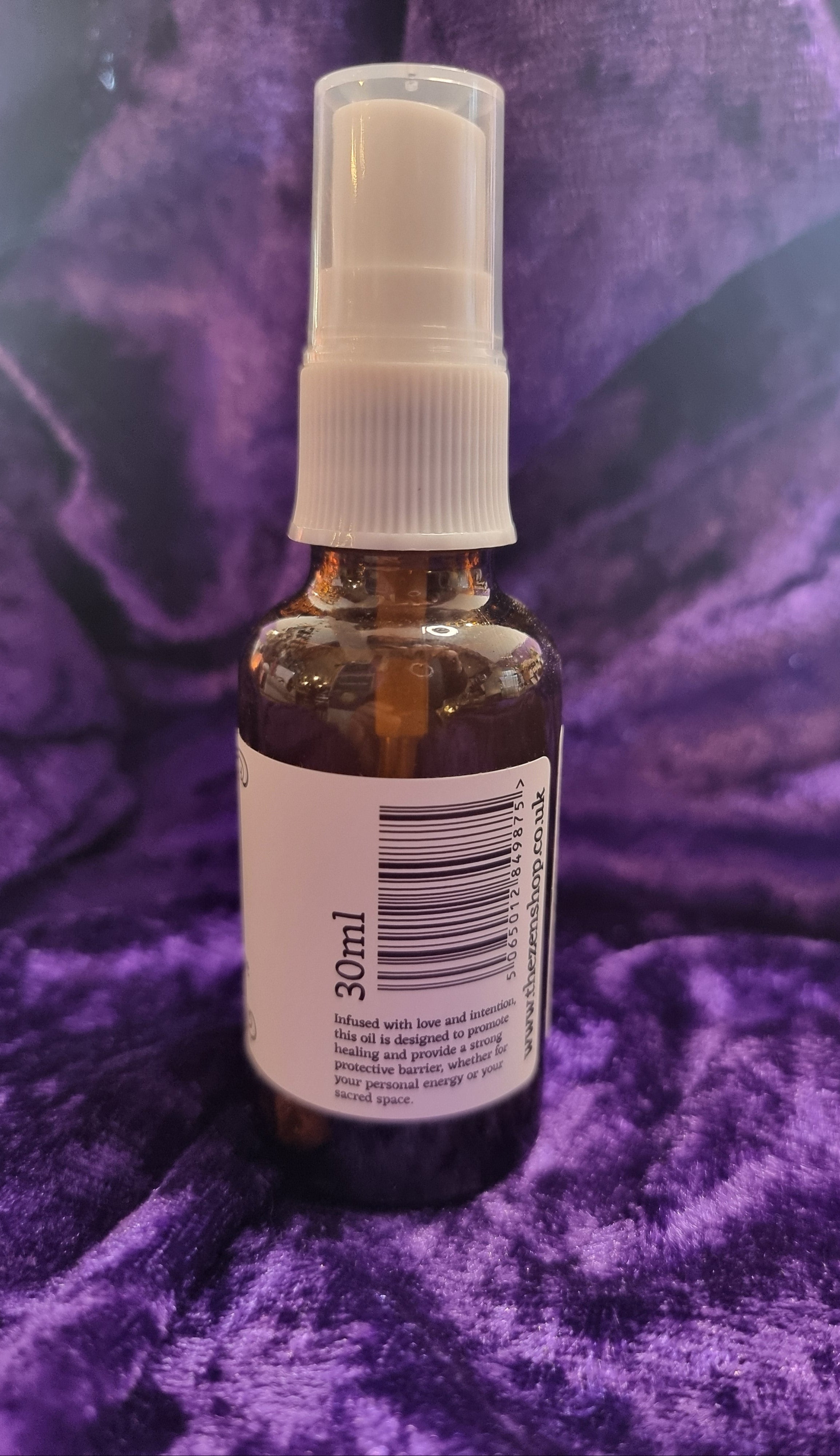 Small spray bottle with a label on a purple textured background