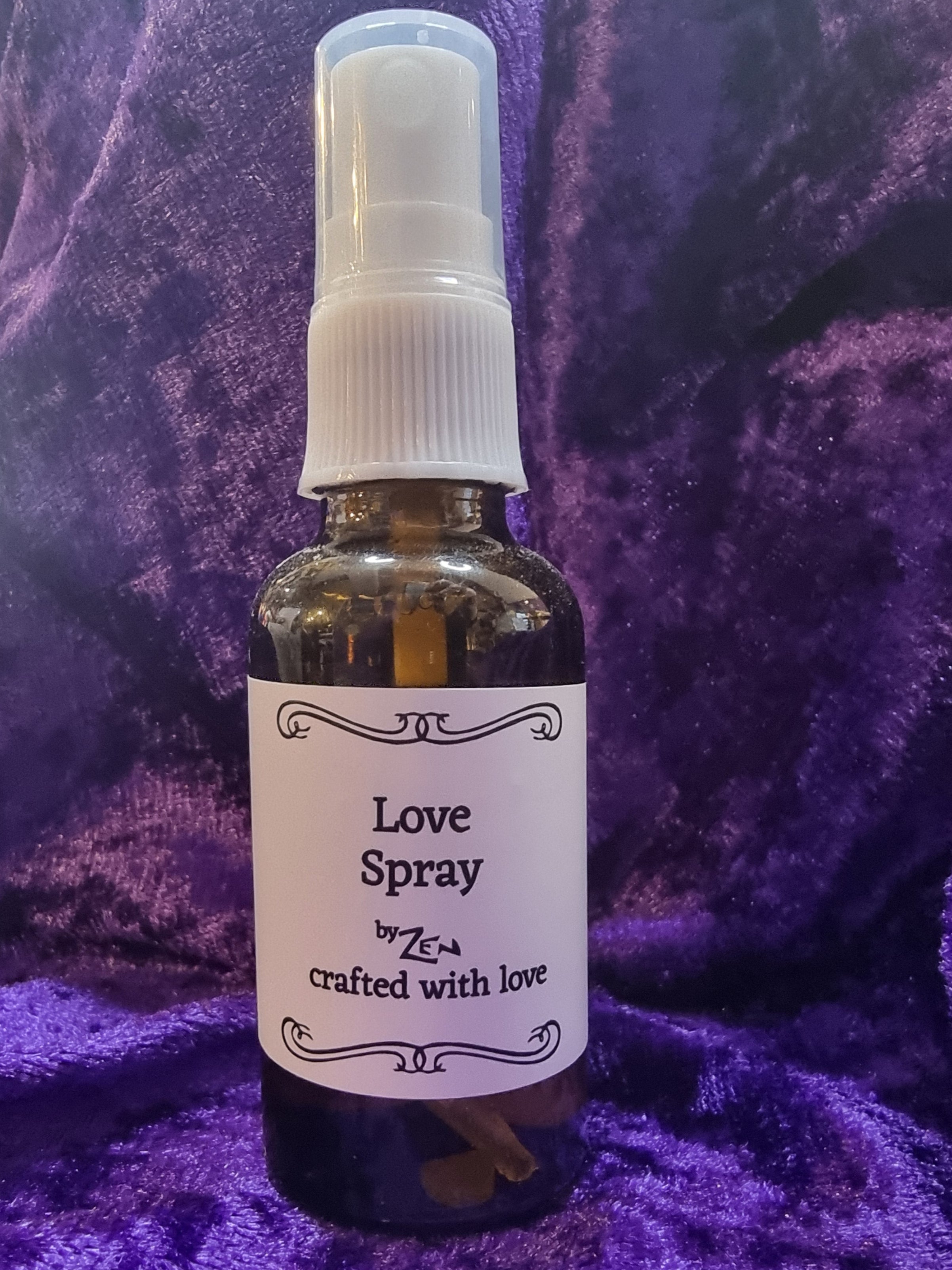Small bottle labeled 'Love Spray' on a purple fabric background