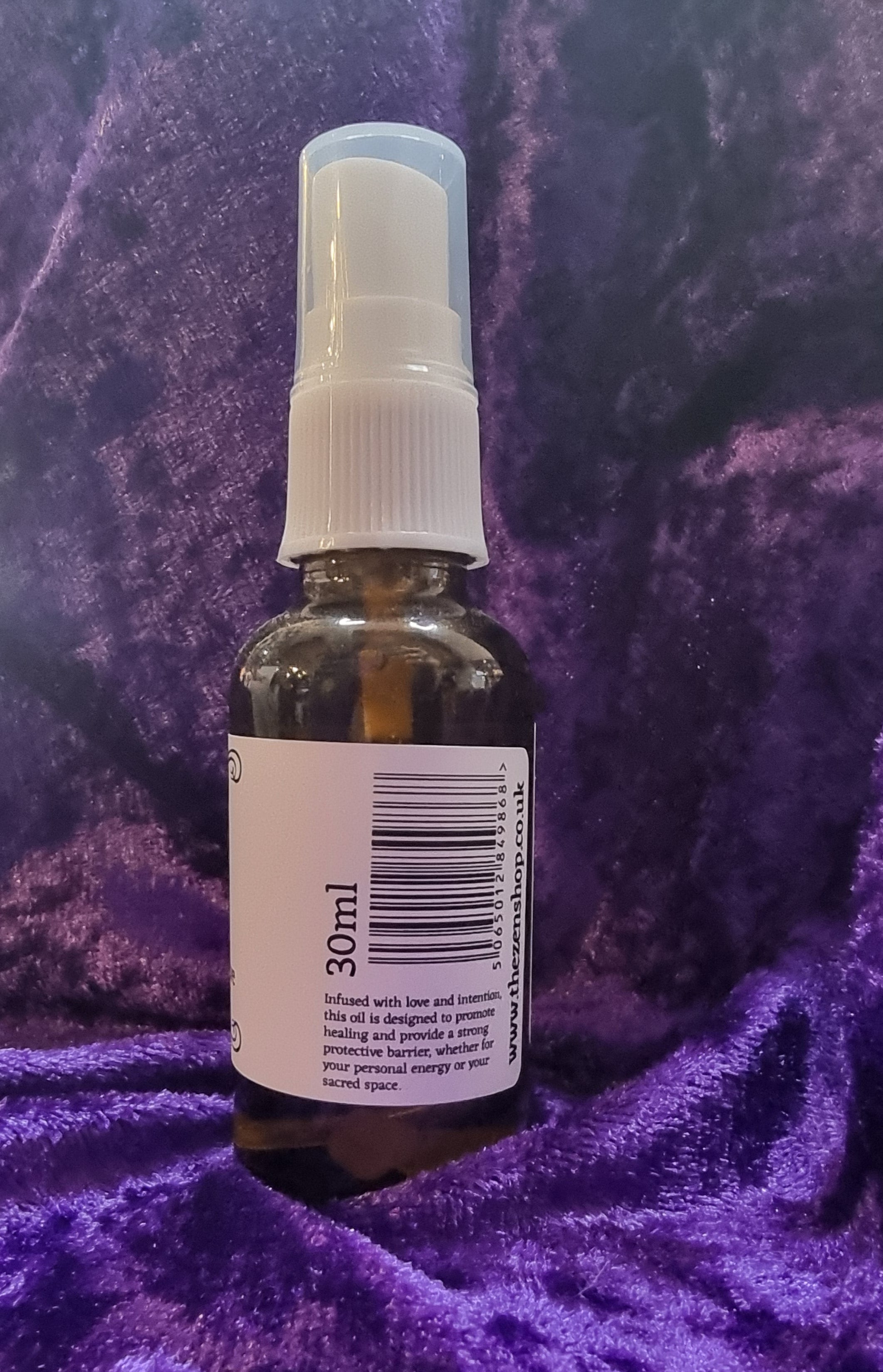 Small bottle with a spray nozzle on a purple textured surface