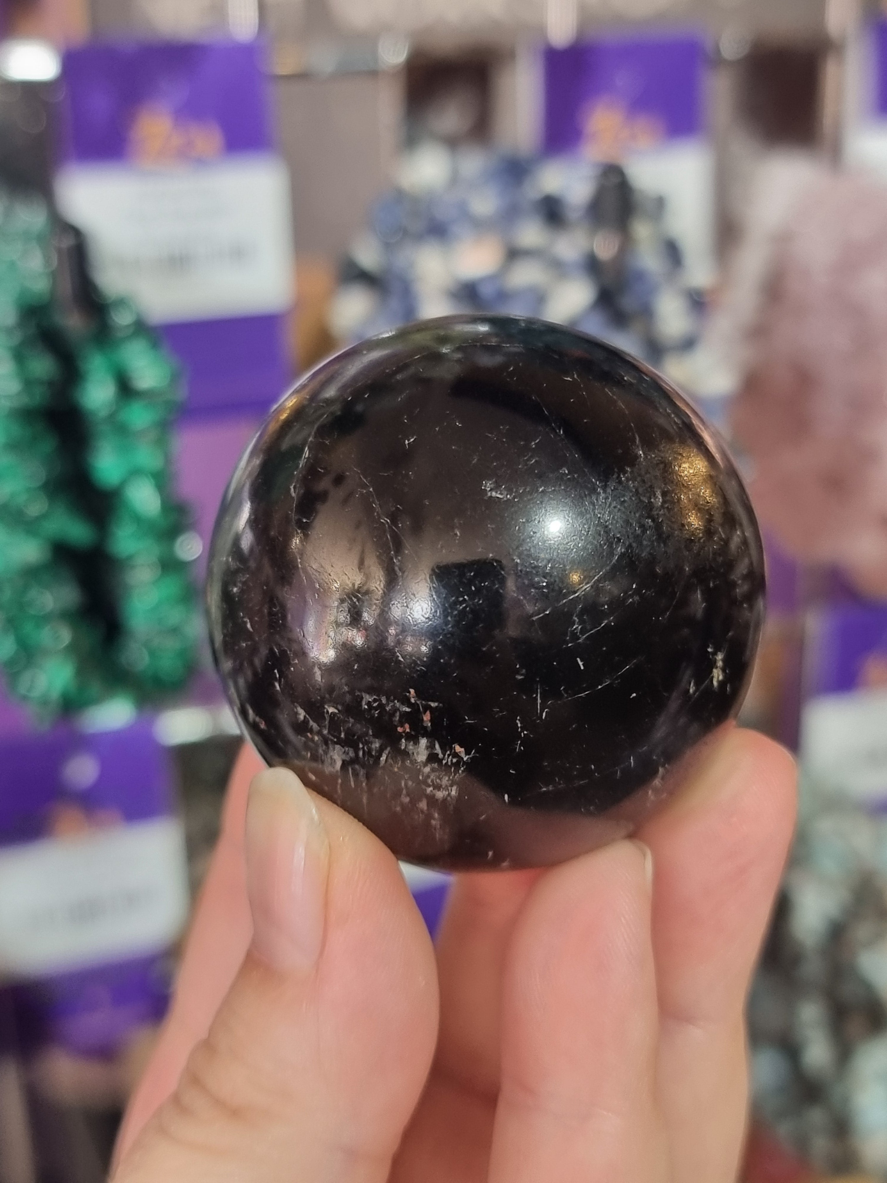 Hand holding a dark crystal ball with a blurred background
