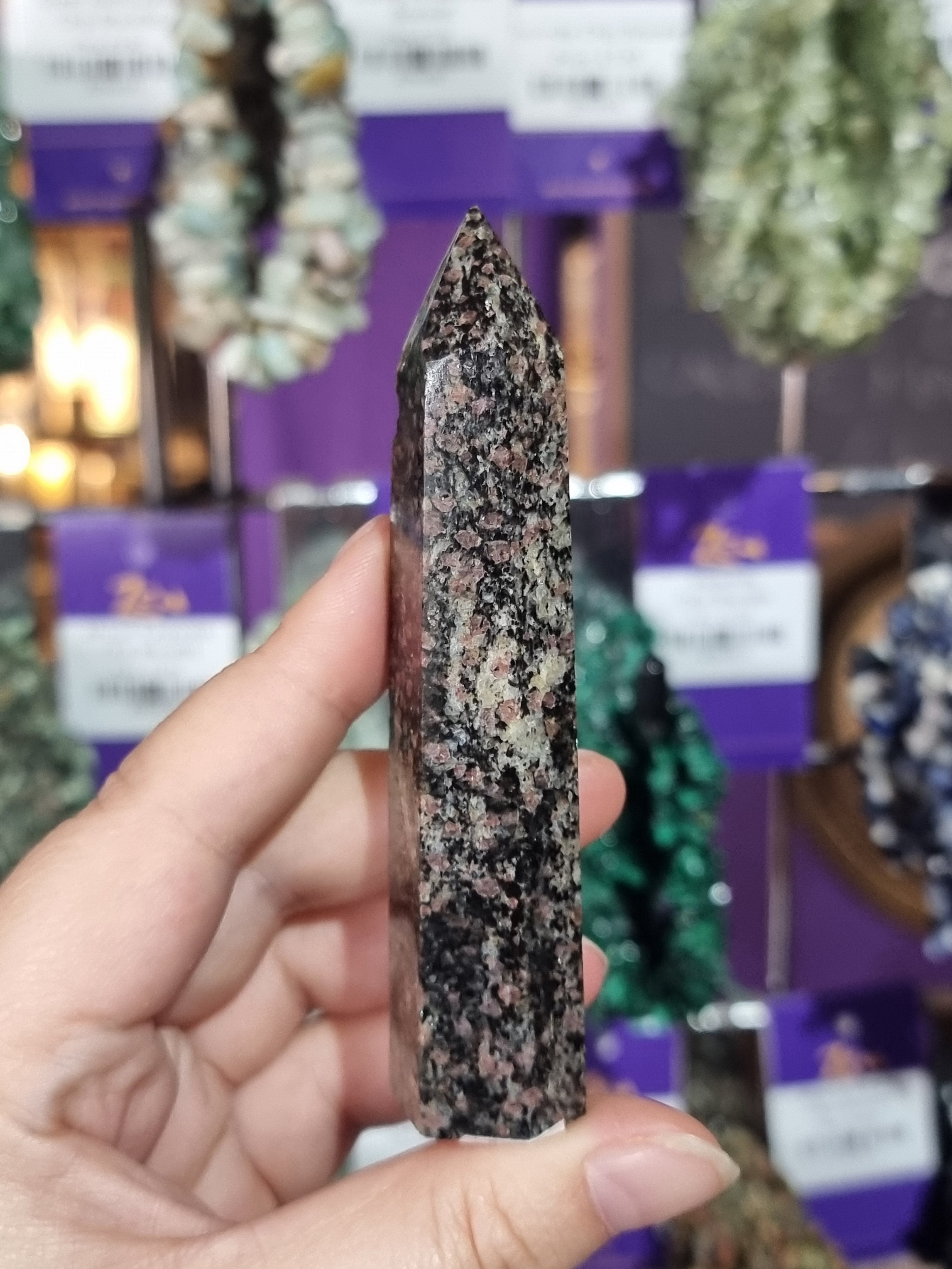 Hand holding a crystal with a blurred store background