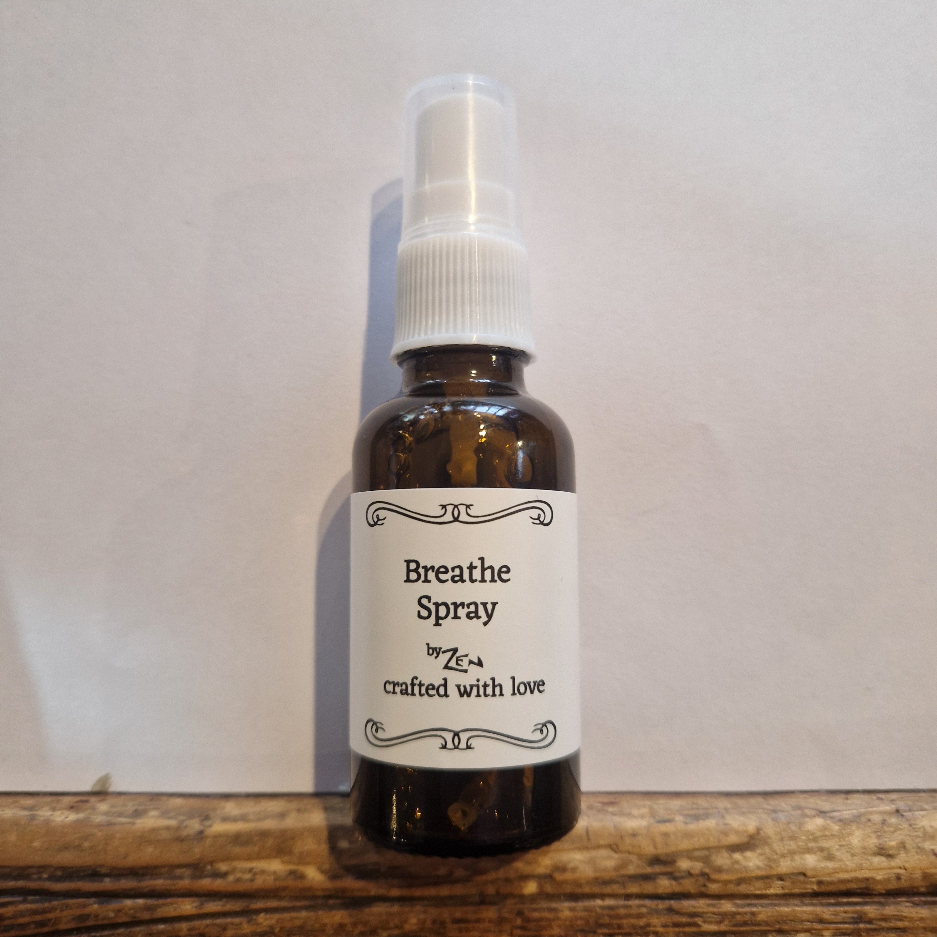 Bottle of 'Breathe Spray' on a white surface with a wooden edge.